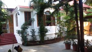a white house with palm trees in front of it at Victoria Villa in Sinquerim