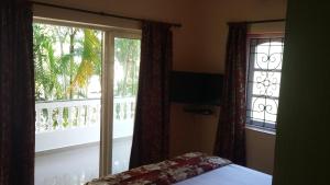 a bedroom with a bed and a window with a balcony at Victoria Villa in Sinquerim