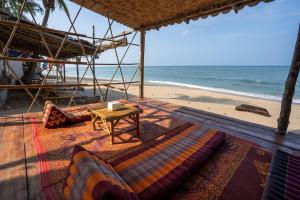 Isara Lanta Beach Resort في كو لانتا: شاطئ فيه كنب وطاولة ومحيط