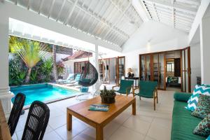 sala de estar con sofá, mesa y piscina en Villa Merah, en Seminyak