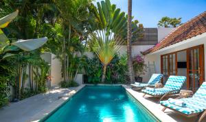 una piscina con sillas y una casa en Villa Merah, en Seminyak