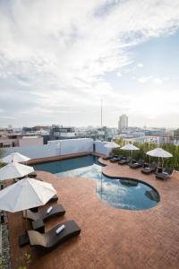 a pool on the roof of a building with umbrellas at Journeyhub Pattaya Central in Pattaya Central
