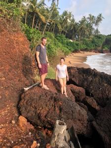 a man and woman standing on a rock on the beach at Manshore bay in Kannur