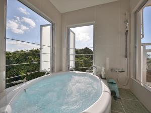 uma banheira na casa de banho com janelas grandes em Hoshi No Terrace Motobu Yamazato em Motobu