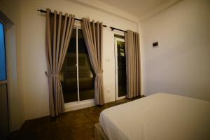 a bedroom with a bed and a window with curtains at Island life in Negombo