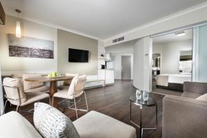 ein Wohnzimmer mit einem Sofa, einem Bett und einem Tisch in der Unterkunft Grand Hotel and Apartments Townsville in Townsville