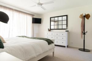 a white bedroom with a bed and a dresser at Nest House Bright in Bright