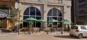 a building with tables and chairs with green umbrellas at Yinm Furnished Apartment in Addis Ababa