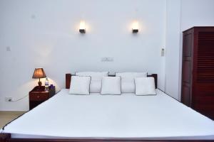 una camera da letto con un grande letto bianco con due cuscini di Minuri Villa a Hikkaduwa