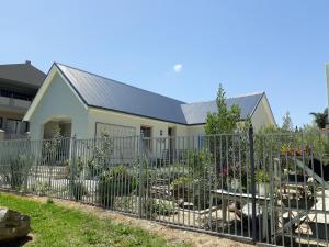 a fence in front of a house with a garden at Nerf-af Cottage and private ROOMs at Onrus , Hermanus in Hermanus