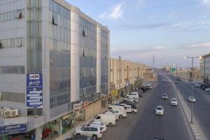 une rue de la ville avec des voitures garées à côté d'un bâtiment dans l'établissement Al Eairy Apartment-Alqaseem 4, à Buraydah