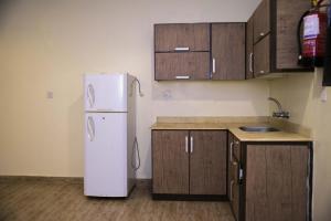 a kitchen with a white refrigerator and wooden cabinets at العييري للشقق المخدومة القصيم 4 in Buraydah +7 photos