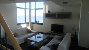 ein Wohnzimmer mit 2 weißen Sofas und einem TV in der Unterkunft Hotel & Restaurant Utkiek in Greifswald