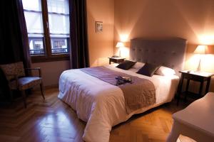 a bedroom with a large bed and two windows at Le Gouverneur Hotel in Obernai