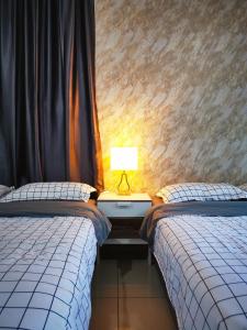 a bedroom with two beds and a lamp on a table at Atlantis Residence Melaka in Malacca