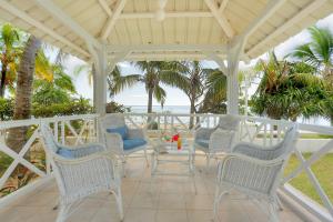 a porch with chairs and a table and the ocean at Cocotiers Hotel - Rodrigues in Rodrigues Island