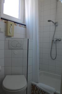 a bathroom with a toilet and a shower with a window at Alleehotel-Eschen in Aurich