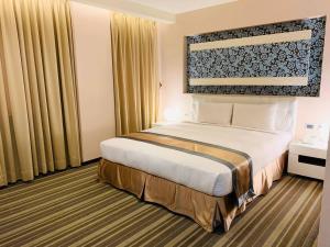 una habitación de hotel con una cama grande y cortinas en Kaishen Sinsu Hotel, en Taitung