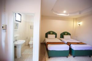 two beds in a small room with a bathroom at The Star Hotel in Udon Thani