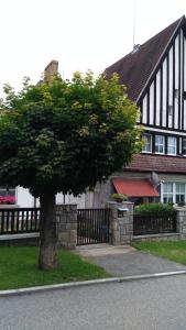 a tree in front of a house with a fence at Byt - apartman in Větřní