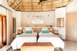 a bedroom with two beds and a bench at Tambuti Lodge in Pilanesberg