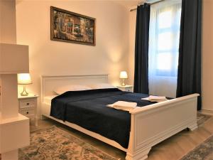 a bedroom with a bed and two lamps and a window at White Wolf Apartment in Braşov