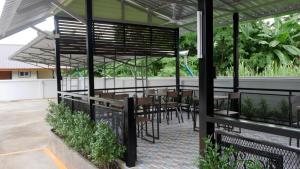 un patio avec des tables et des chaises sous une pergola dans l'établissement Sangthong Building, à Mae Chaem