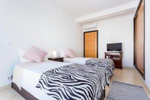 een hotelkamer met 2 bedden en een televisie bij Ouranascente in Albufeira