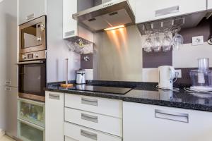een keuken met witte kasten en zwarte aanrechtbladen bij Ouranascente in Albufeira