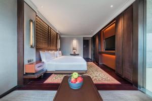 a hotel room with a bed and a bowl of fruit on a table at Regent Chongqing in Chongqing