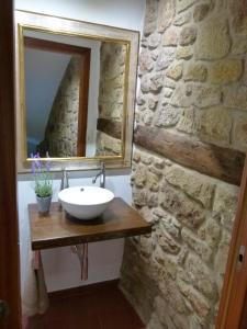 a bathroom with a sink and a mirror on a stone wall at Casa rural Villanueva in Mora de Rubielos