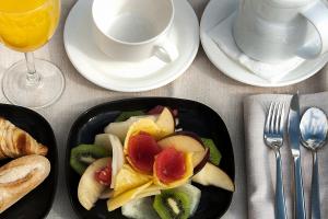 a table with a plate of fruit and a cup of coffee at Silken Ramblas in Barcelona
