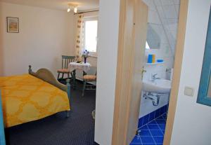 a room with a bathroom with a sink and a bed at Selliner Pension am Waldrand in Ostseebad Sellin