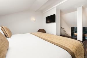a white bedroom with a bed and a tv at Áurea Legends by Eurostars Hotel Company in Prague