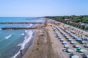 eine Aussicht über einen Strand mit Sonnenschirmen und Menschenmengen in der Unterkunft Villaggio San Francesco in Duna Verde