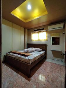 a large bed in a room with a yellow ceiling at Jati Classic Homestay in Banyuwangi