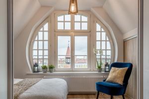 a bedroom with a large window and a blue chair at Apartamenty Katrin Home in Toruń
