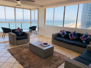 a living room with couches and a table and chairs at The Penthouses Apartments in Gold Coast