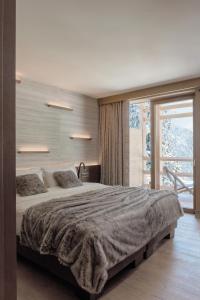 a bedroom with a large bed and a large window at Lefay Resort & SPA Dolomiti in Pinzolo