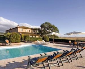 a pool with chairs and umbrellas and a building at Tenuta La Casetta in Casciana Terme