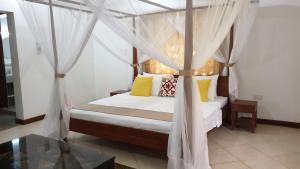 a bedroom with a canopy bed with yellow pillows at Villa Oman in Bwejuu