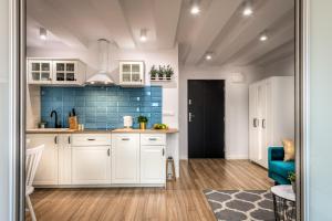 a kitchen with white cabinets and a blue tile wall at Apartamenty Katrin Home in Toruń