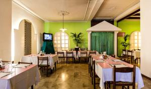 a dining room with tables and chairs and green walls at Hotel Villarosa con Vespa Rent in Sarroch