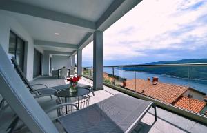 ein Balkon mit Tisch und Stühlen und Blick auf das Wasser in der Unterkunft Apartment Vanilla II with beautiful Seaview in Rabac