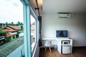 a room with a balcony with a desk and a window at Queen Boutique Hotel Chaweng in Chaweng