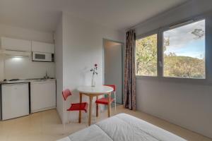 a bedroom with a table and red chairs and a kitchen at City Résidence Sophia in Valbonne