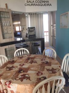 a dining room with a table and chairs and a kitchen at apartamento 4 praças in Torres