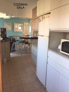 uma cozinha com um frigorífico branco e uma mesa em apartamento 4 praças em Torres