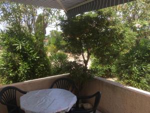 une table et deux chaises sur un balcon arboré dans l'établissement Maison de plein pied à Barcares, au Barcarès