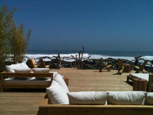 a group of couches on a beach with the ocean at Hotel 8 al Mar in Pichilemu